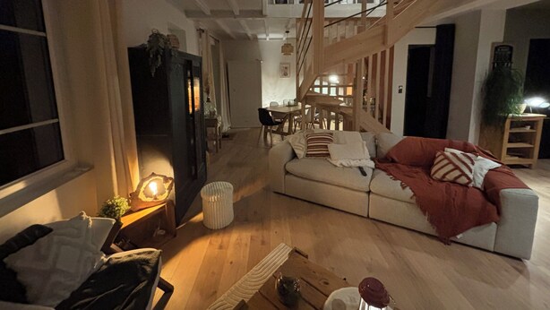 A cozy living room with a sofa, a coffee table, and a staircase.