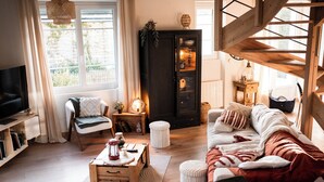 A cozy living room with a fireplace, a television, a sofa, and a wooden coffee table.