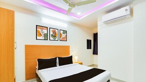 Een hotelkamer met een bed, een plafondventilator, een airconditioner en kunst aan de muur.