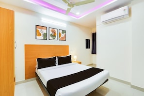 A hotel room with a bed, a ceiling fan, an air conditioner, and wall-mounted artwork. - Deluxesri Balaji Luxury Rooms (Hyderabad)