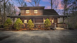 A two-story wooden cabin with a porch, surrounded by trees. - Rocky Top Sports World - 7 mins, Gatlinburg getaway w/Hot tub & Outdoor games (Gatlinburg)
