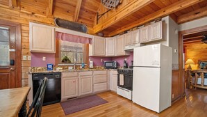 A kitchen with wooden cabinets, a refrigerator, a microwave, and a stove. - Rocky Top Sports World - 7 mins, Gatlinburg getaway w/Hot tub & Outdoor games (Gatlinburg)