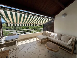 Een balkon met een gestreept zonnescherm, een bank, een tafel en stoelen.