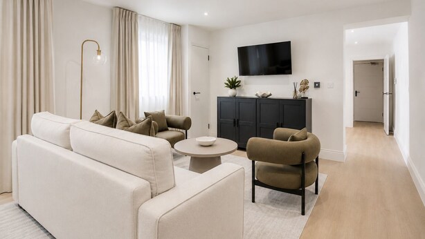 Uma sala de estar moderna com sofá, poltronas, mesa de centro e televisão na parede.