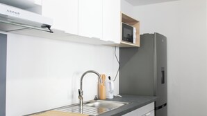 Cuina moderna amb un vàter d'acer inoxidable, una taula de tall de fusta i un microones integrat sobre el taulell.