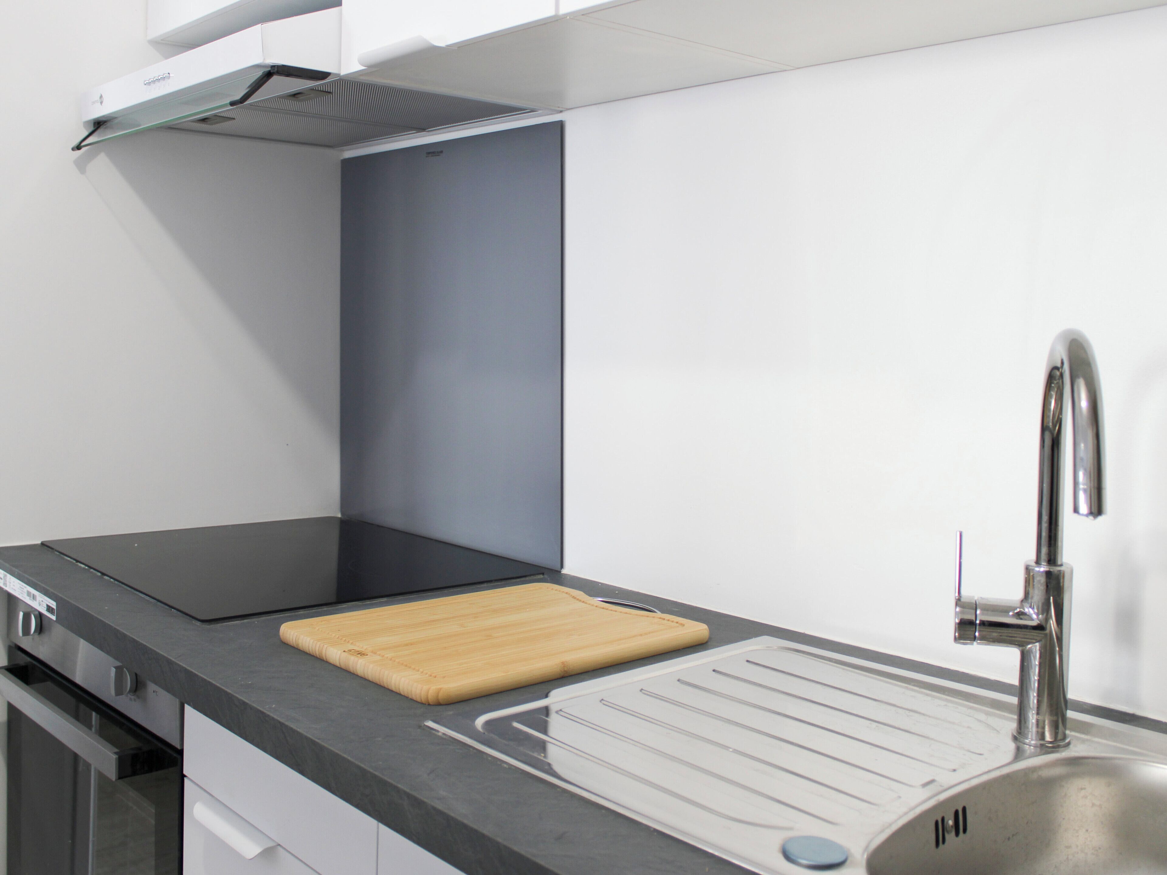Een moderne keuken met een roestvrijstalen spoelbak, een houten snijplank en een ingebouwde kookplaat.