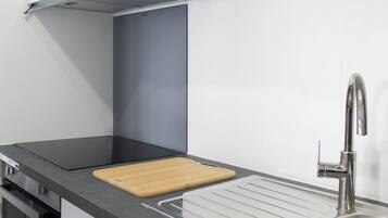 Een moderne keuken met een roestvrijstalen spoelbak, een houten snijplank en een ingebouwde kookplaat.