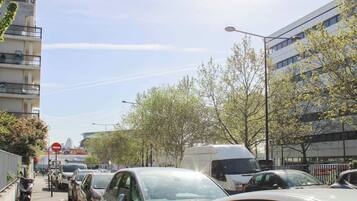 A street lined with parked cars and buildings, a clear sky, and a no entry sign.