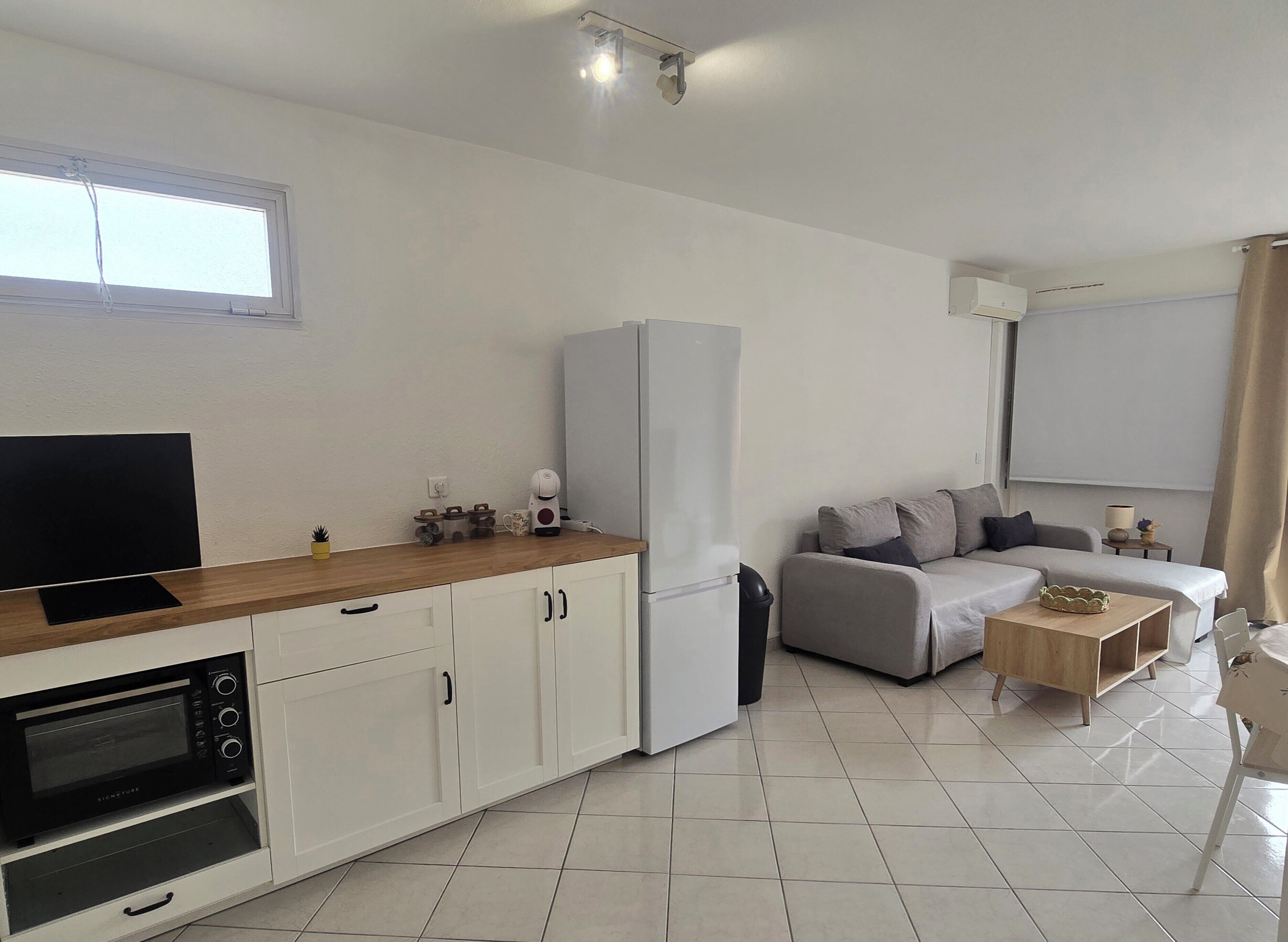 A modern kitchen with a built-in microwave, a refrigerator, and a coffee maker on the counter.