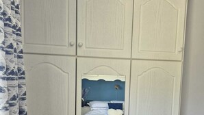Une chambre à coucher avec un lit, une table de chevet et une armoire avec un miroir.