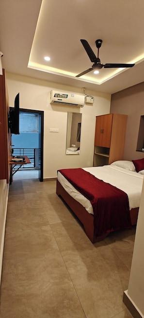 A bedroom with a bed, a ceiling fan, an air conditioning unit, a wardrobe, and a mirror. - AKSHAYA COMFORTS (Visakhapatnam)