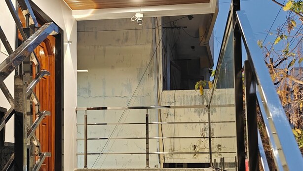 A staircase leading to a room with a wooden ceiling and a glass wall. - AKSHAYA COMFORTS (Visakhapatnam)