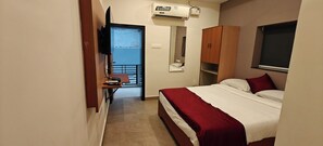 A bedroom with a bed, a TV, a wardrobe, a mirror, and an air conditioning unit. - AKSHAYA COMFORTS (Visakhapatnam)