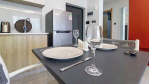 A modern dining area with a black table, white plates, and a wine glass. - Annbell Haven 1br, With Pool, Near Junct (Nairobi)