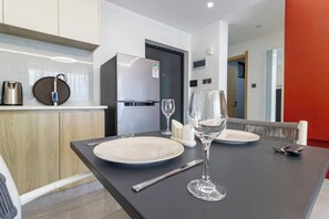 Un espace de salle à manger moderne avec une table noire, des assiettes blanches et des verres à vin.