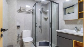 A modern bathroom with a glass-enclosed shower, a toilet, a sink, and a mirror. - Annbell Haven 1br, With Pool, Near Junct (Nairobi)