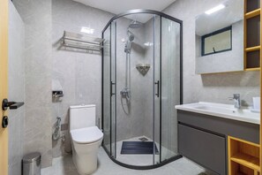Une salle de bain moderne avec une douche à parois de verre, des toilettes, un lavabo et un miroir.