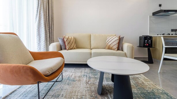 A modern living room with a sofa, a round coffee table, and a chair. - Annbell Haven 1br, With Pool, Near Junct (Nairobi)