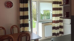 A dining area with a table and chairs, a clock on the wall, and a window with curtains. - By trails and parks, near cafés, 25 min from Energylandia. (Bielsko-Biała)