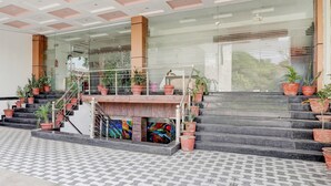 A hotel entrance with a staircase, glass doors, and potted plants. - Deluxe Hotel Kc Royal (Dera Bassi)