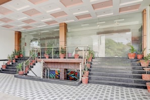 A hotel entrance with a staircase, glass doors, and potted plants.