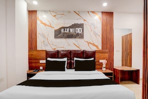 A hotel room with a bed, wooden headboard, a nightstand, a phone, a mirror, and a wall with a 'Hollywood' sign.