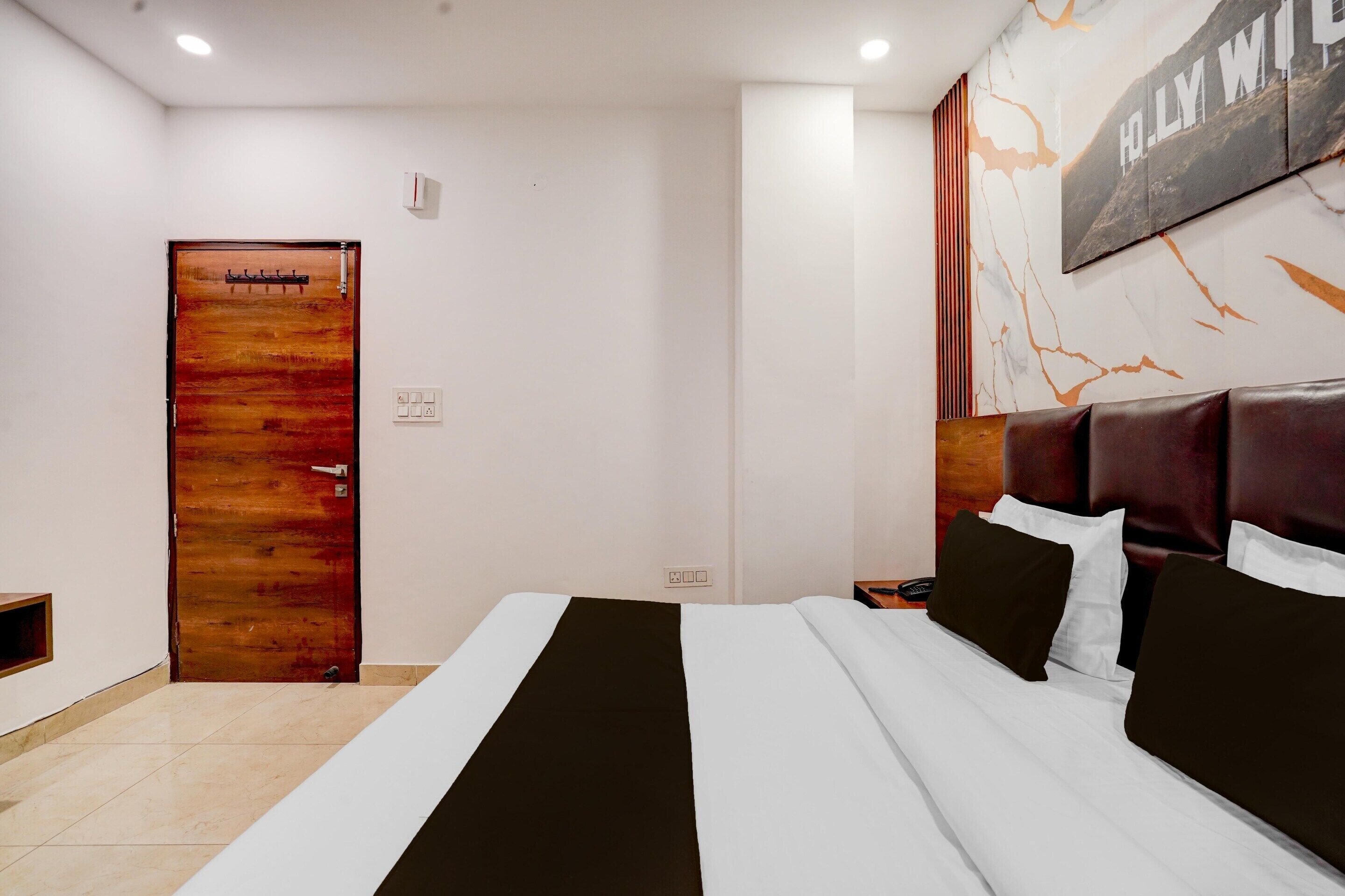 Ein Hotelzimmer mit Bett, Holztür, Wandbild und Nachttisch.