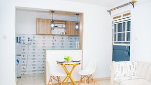 A compact living space with a kitchenette, a dining area with a small table and chairs, and a sofa. - Serene 1-bedroom apartment in Nairobi perfect for your stay (Nairobi)