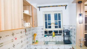 A kitchen with wooden cabinets, a window, a sink, and a shelf with kitchen items. - Serene 1-bedroom apartment in Nairobi perfect for your stay (Nairobi)