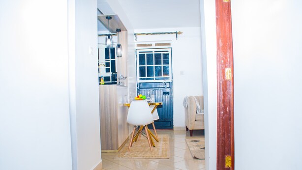 A hallway leading to a kitchen with a dining table, chairs, and a red door. - Serene 1-bedroom apartment in Nairobi perfect for your stay (Nairobi)