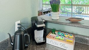 Una estación de café con una máquina de espresso, una cafetera y una caja de cápsulas de café.