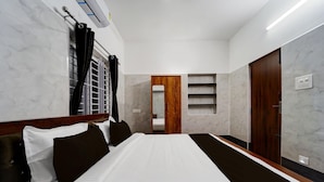 Ein Hotelzimmer mit Bett, Kleiderschrank, Spiegel, Ablagefläche und Tür.