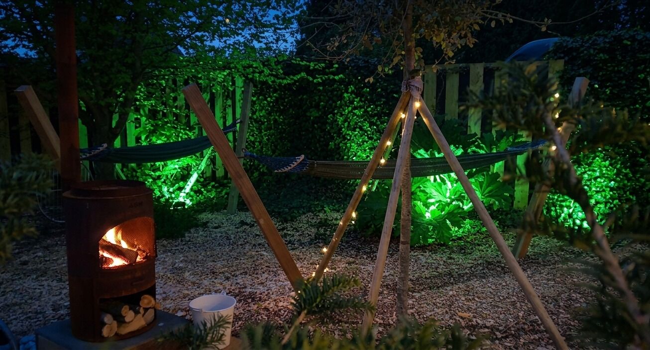 Un cadre extérieur rustique avec un poêle à bois, un hamac et des guirlandes lumineuses.