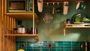 Cozinha com micro-ondas, utensílios pendurados e painel de azulejos verdes.