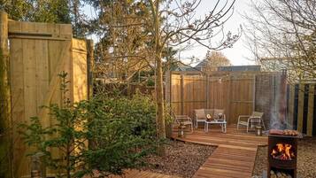 Une terrasse en bois avec des meubles d’extérieur, un foyer et une clôture en bois.