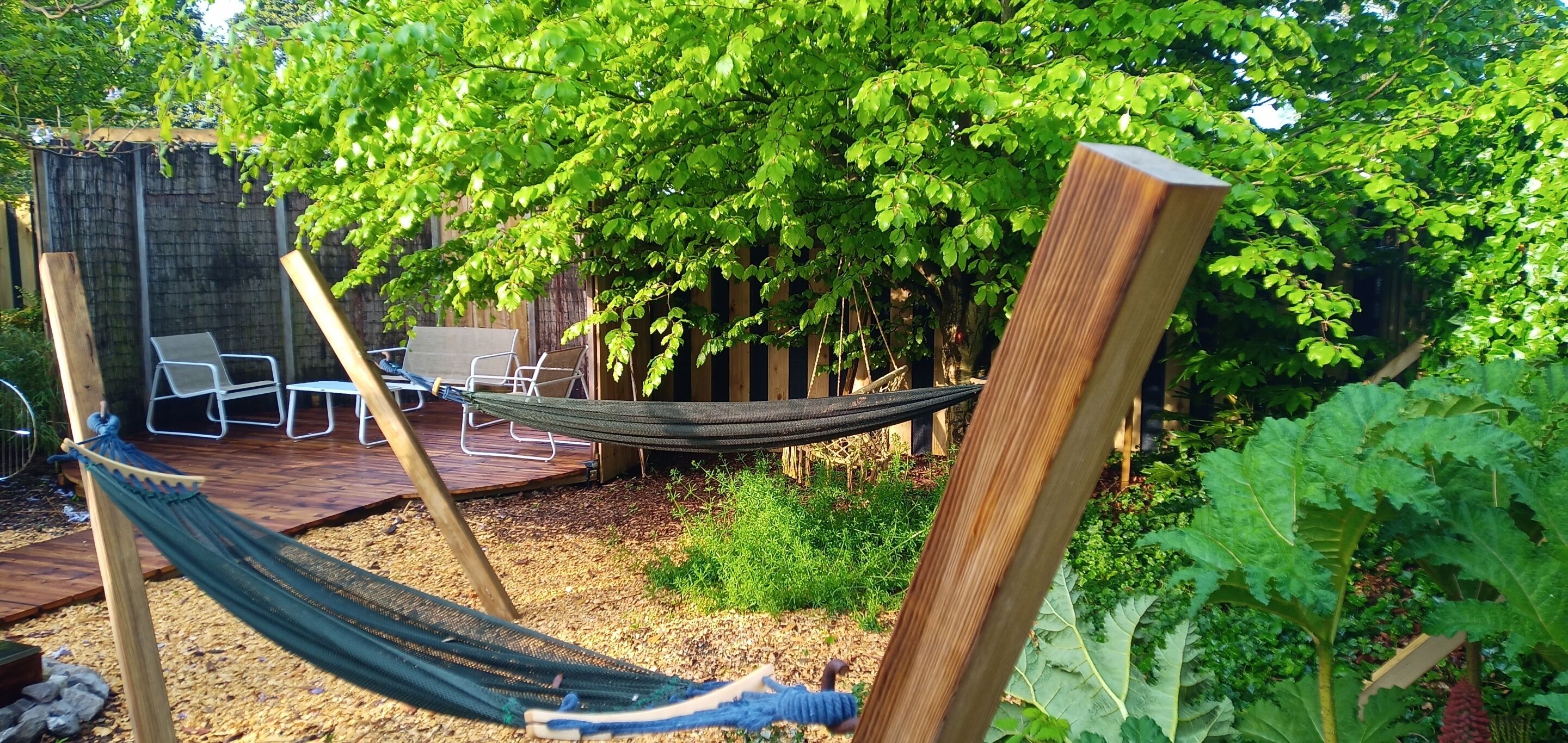 Un hamac, du mobilier d’extérieur et une terrasse en bois, le tout dans un cadre de jardin.