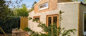 A small wooden cabin with a sloped roof, two windows, and a wooden deck. - Tiny house perdue logement insolite Baie de Somme (Saint Blimont)