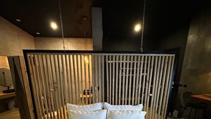 A bed with a white quilt and pillows, a wooden headboard, and a hanging light fixture. - Charming 1-bedroom with Ocean View - A God's View (Las Palmillas)