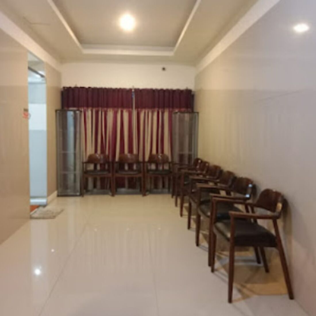 A conference room with a long table and chairs, a glass partition, and a red curtain.
