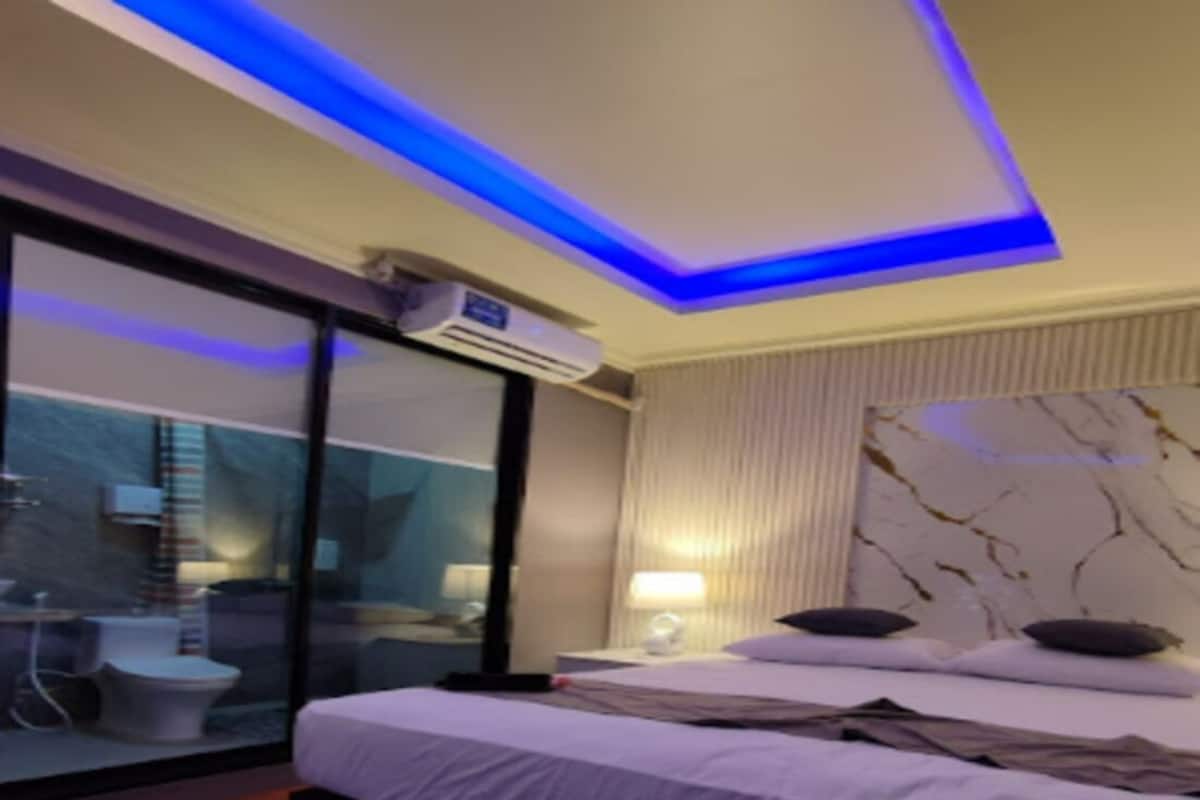 Et moderne hotelværelse med seng, sofa, badeværelse med toilet og håndvask samt et stort vindue.