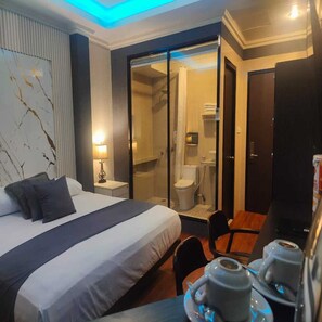A hotel room with a bed, a desk with a tray of cups, a shower area, and a door. - Hot In Hotel (Depok)