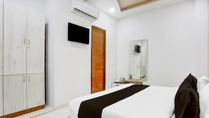 A hotel room with a bed, wardrobe, TV, mirror, and air conditioning unit. - Super Deluxe Room Mohini Guest House (Bareilly)
