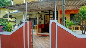 A building entrance with a red and white gate, a tiled floor, and a covered area with a metal roof. - Deluxecrystal Holiday Homes (Calangute)