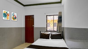 A bedroom with a bed, a window with curtains, a door, and two framed artworks on the wall. - Deluxecrystal Holiday Homes (Calangute)