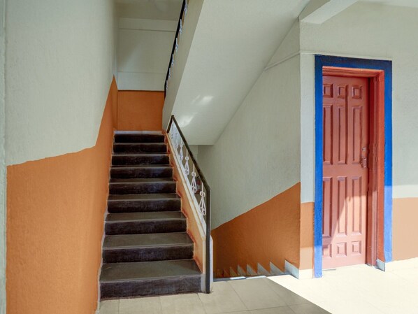 A staircase with a handrail, a door with a red frame, and a wall with a two-tone color scheme.
