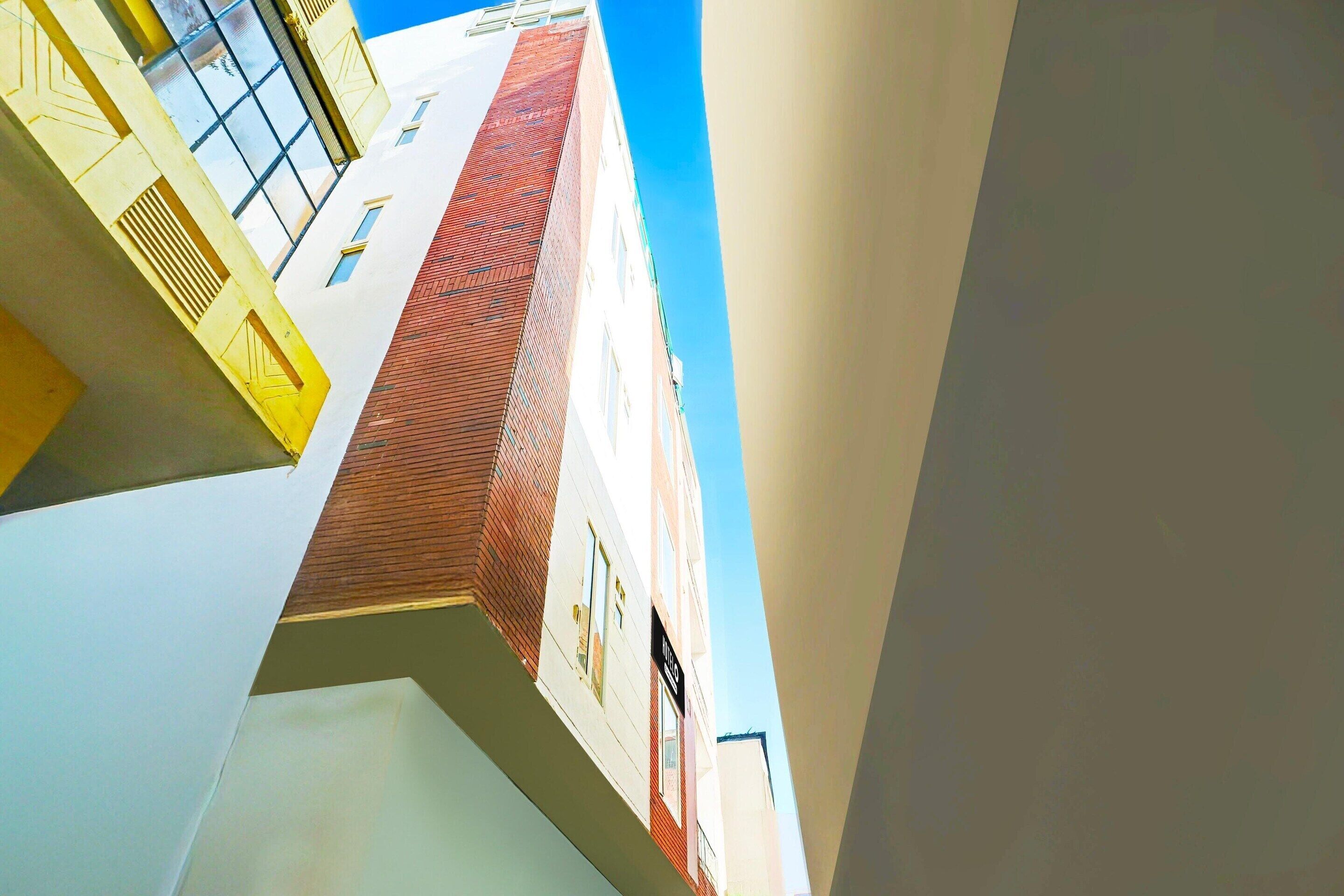 A multi-story building with a red brick facade, white walls, and a clear blue sky.