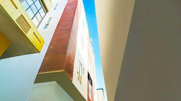 A multi-story building with a red brick facade, white walls, and a clear blue sky.