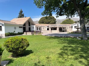 A building with a tiled roof, a covered patio area, and a well-maintained lawn.