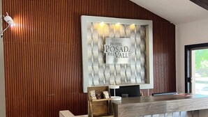 Una recepción de hotel con diseño moderno, un ventilador de techo y un letrero que dice 'Hotel Posada del Valle'.