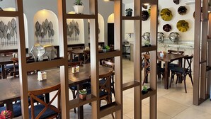 Un restaurante con mobiliario de madera, una pared decorada con platos y un techo con vigas a la vista.